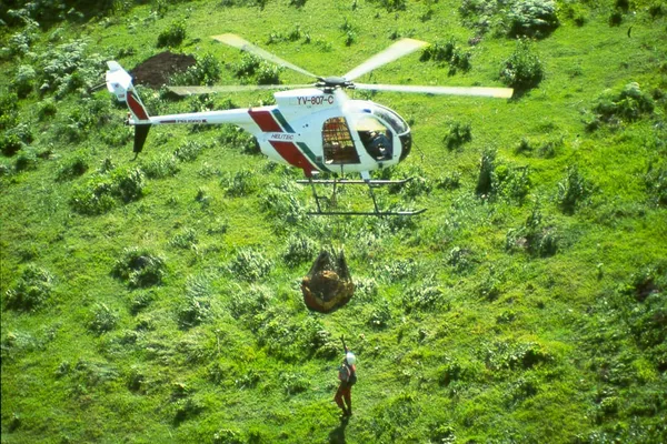 Helicóptero MD Helitec con eslinga de carga externa sobre vegetación